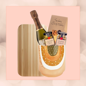 Toast & Taste Celebration Kit in an eco-friendly plant pot, featuring a mini bottle of champagne, gourmet nibbles, antipasto, and a bamboo serving board, wrapped in sustainable materials."